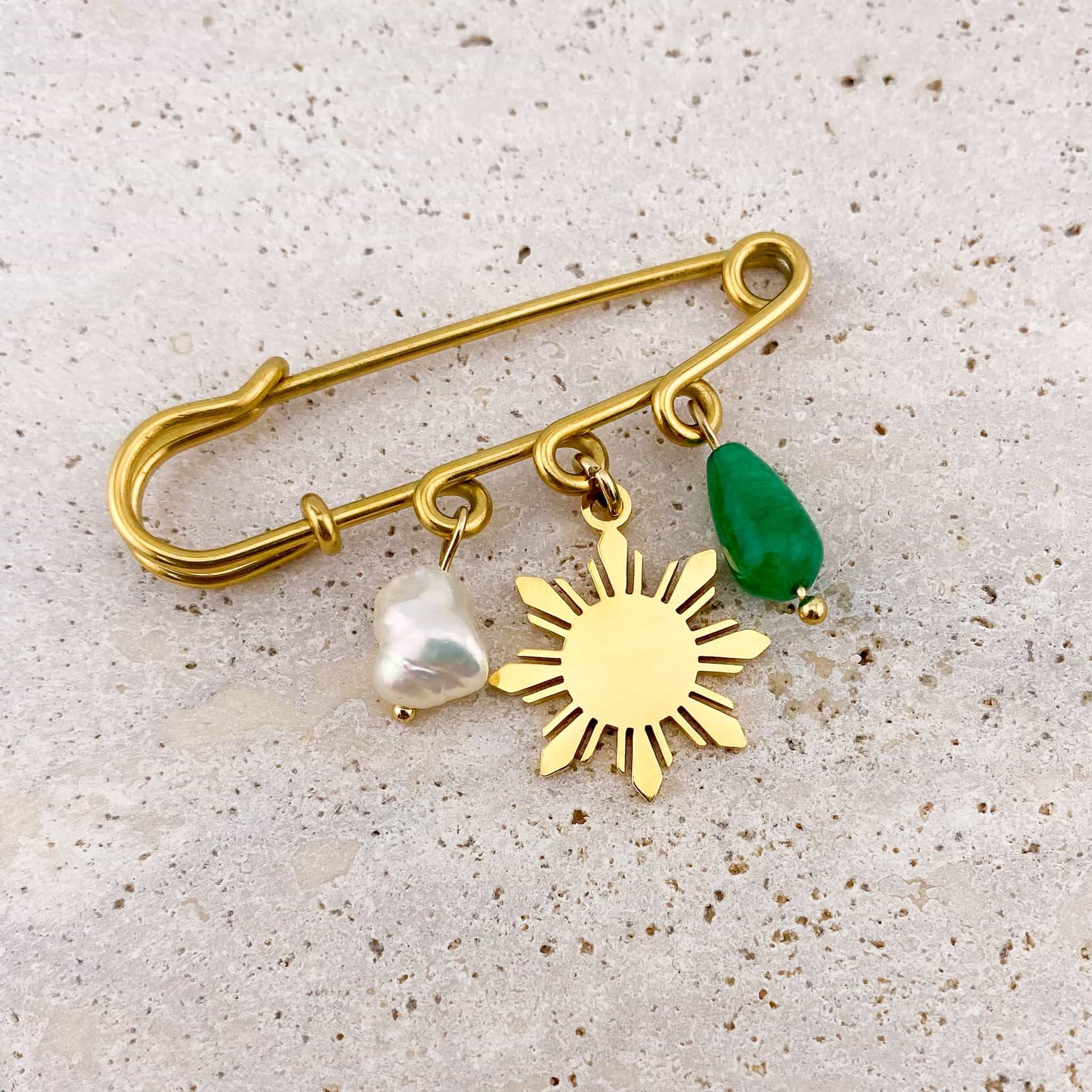 Aking Sinta Safety Pin Brooch with pearl, Araw sun, and jade charms displayed on rock-textured background, highlighting intricate design and Philippine-inspired details