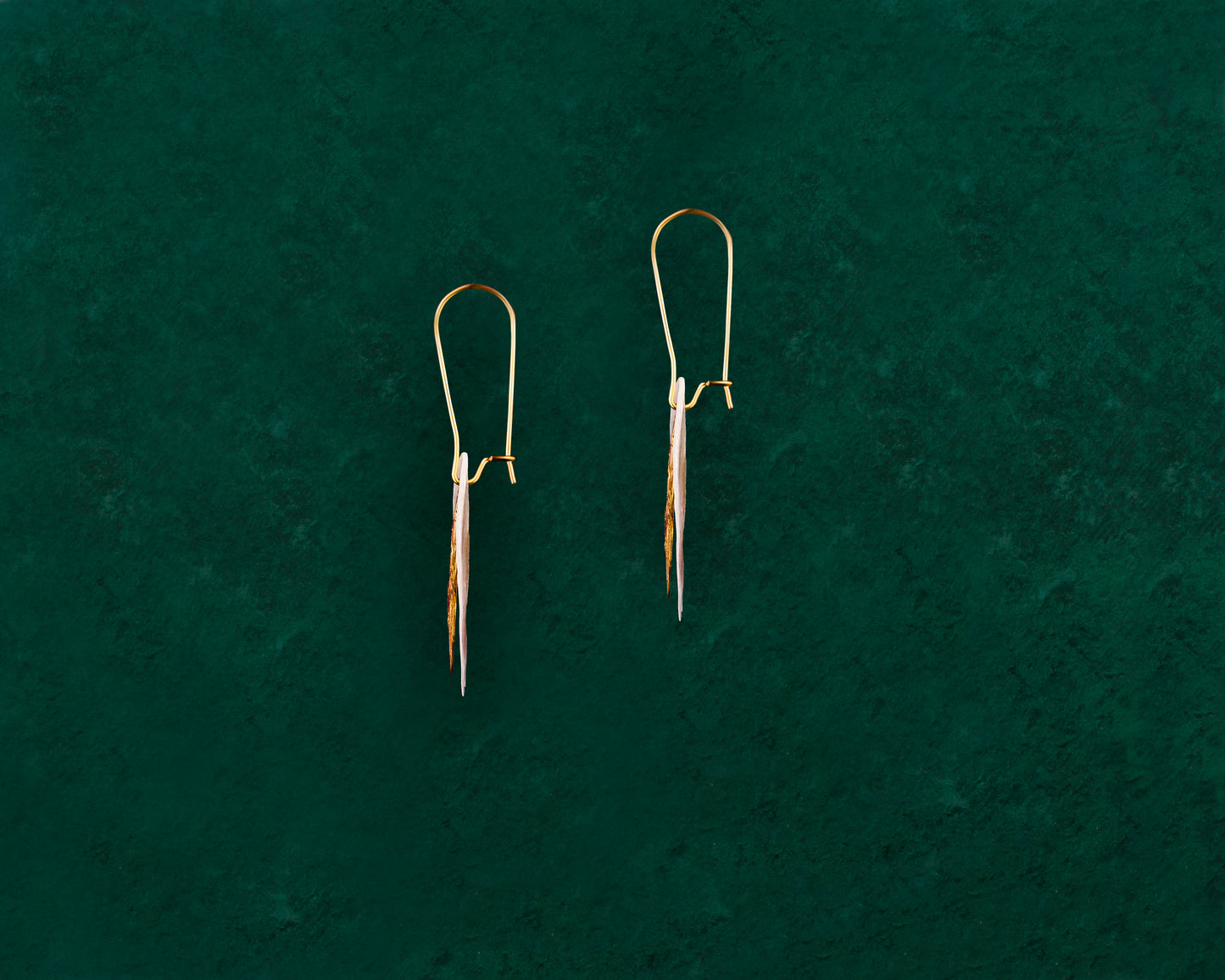Side profile view of an Aking Sinta Charmed Capiz Shell earring on a dark green background; a gold Sampaguita flower charm with detailed petals is layered over a round, translucent white Capiz shell disk, hanging from a gold hook.