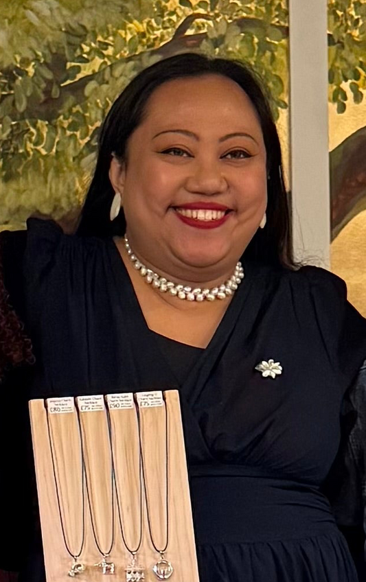 Close-up lifestyle shot of the Aking Sinta Sampaguita brooch with white pearl petals and a green malachite center, worn on a black dress.