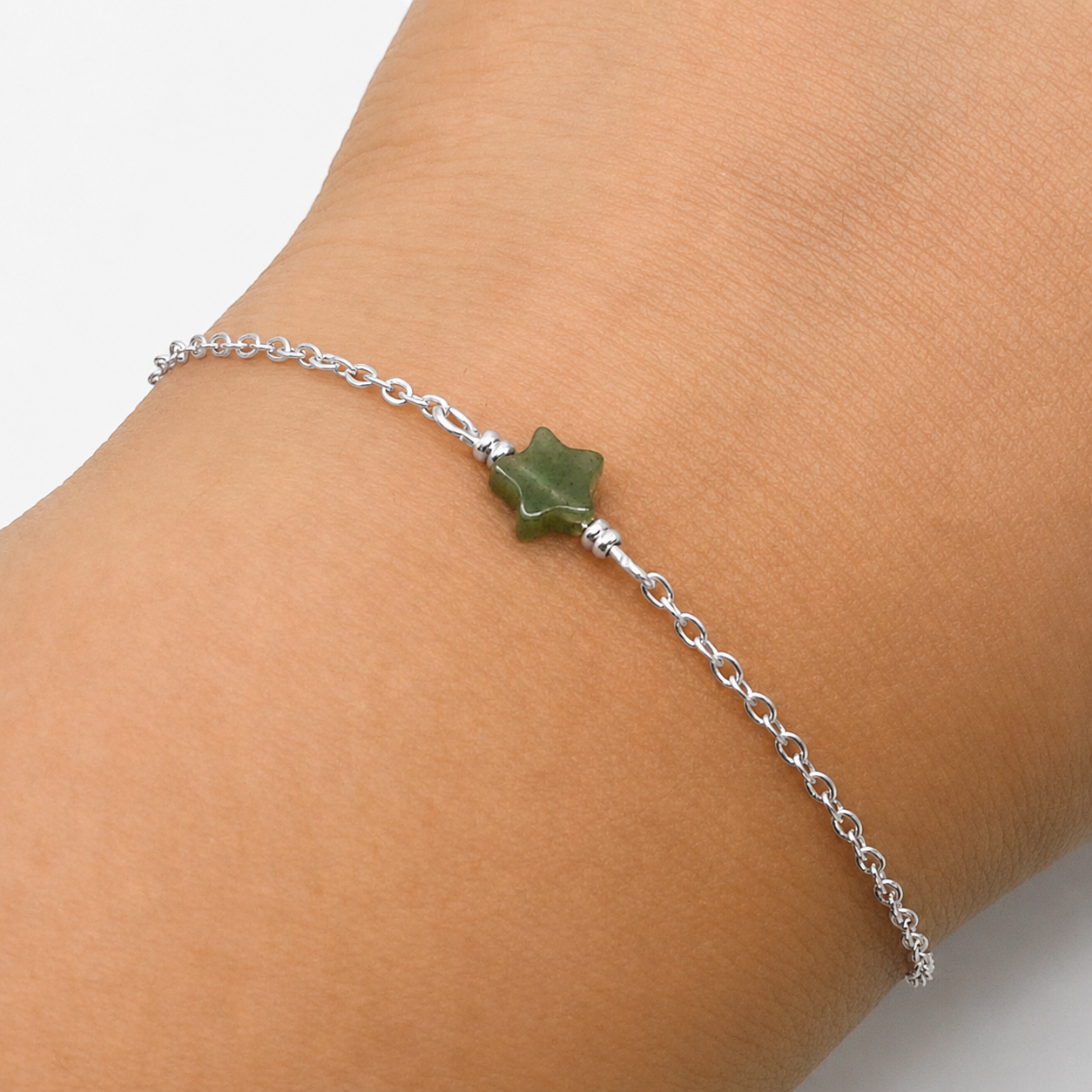 An Aking Sinta product photograph showcasing a dainty green aventurine star bracelet worn on a wrist against a clean white background. The delicate silver chain bracelet features a small star-shaped green aventurine gemstone charm at the center, flanked by tiny silver accent beads.
