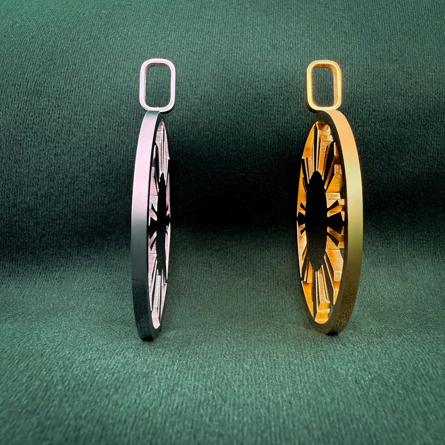 A side-profile view of the Aking Sinta statement Araw medallions in polished silver and gold, highlighting the depth and sculptural quality of the sun-inspired, filigree-cut design. The medallions are displayed against a rich, dark green velvet background, emphasizing their modern, architectural silhouette