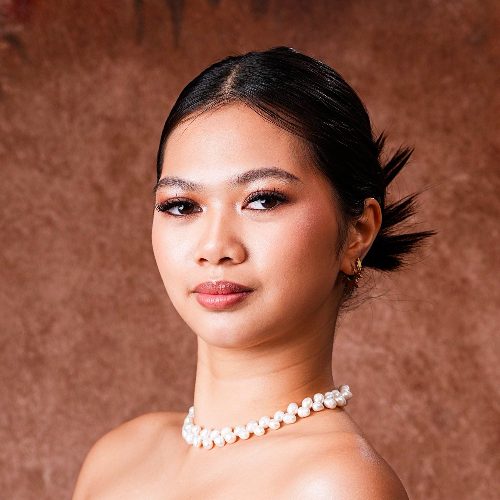 Close-up of a model wearing the Aking Sinta Wheat Pearl Necklace, showcasing the unique wheat-stalk pearl arrangement and iridescent luster against the neckline.
