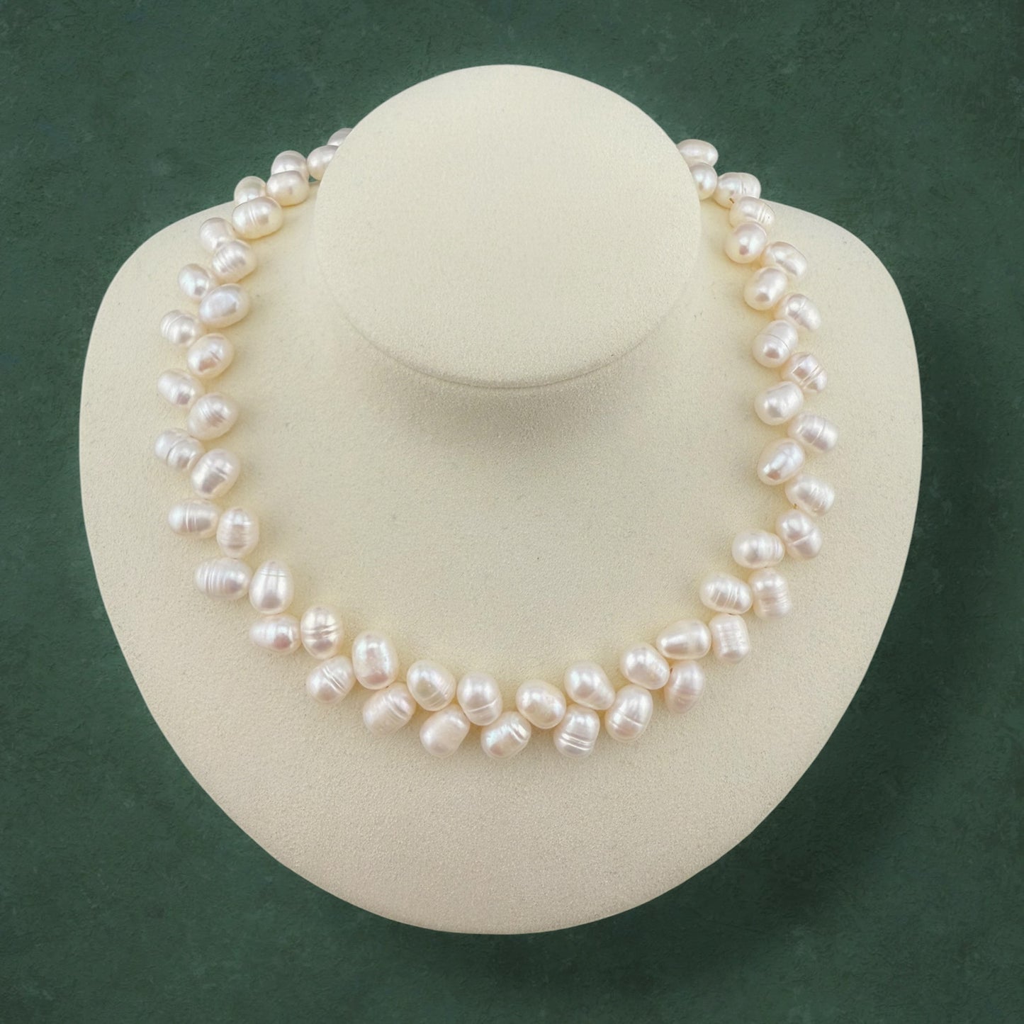 Aking Sinta Wheat Pearl Necklace featuring a textured, grain-stalk arrangement of rice pearls, displayed on a white jewelry bust against a dark green background.