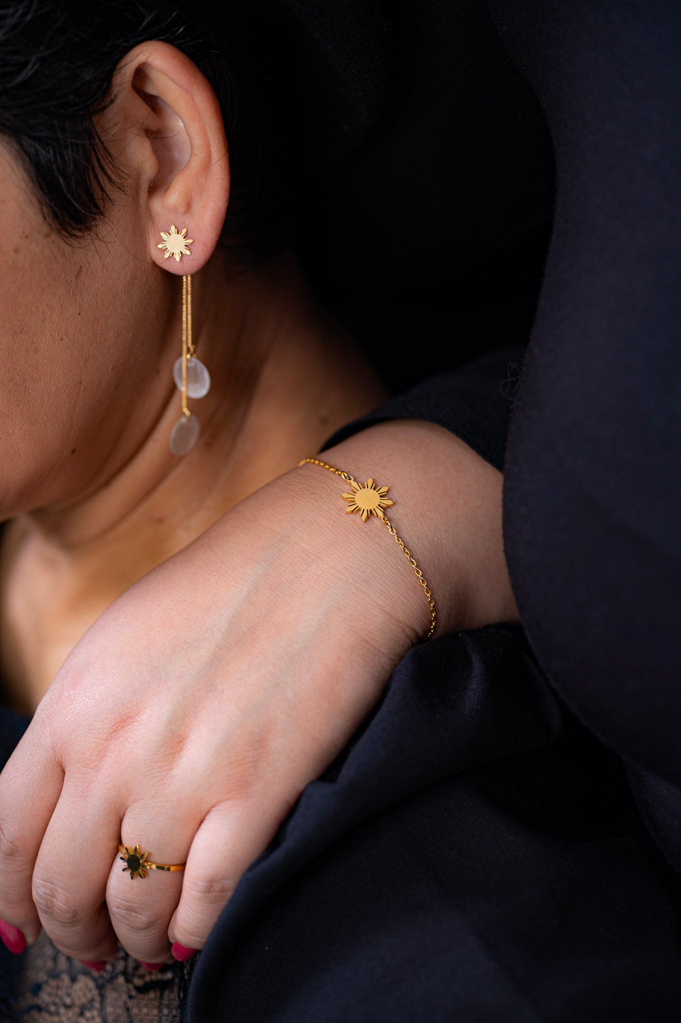A close-up of a hand wearing the Araw gold sun bracelet resting on the shoulder of the founder's mother, symbolizing a timeless connection and ageless jewelry design