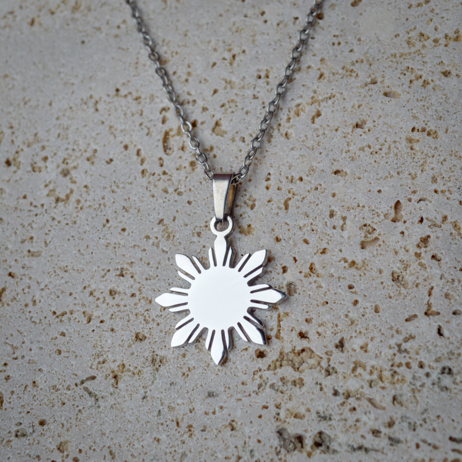Araw minimalist silver sun pendant necklace displayed on a white marble background, sleek polished finish jewelry for a modern aesthetic.