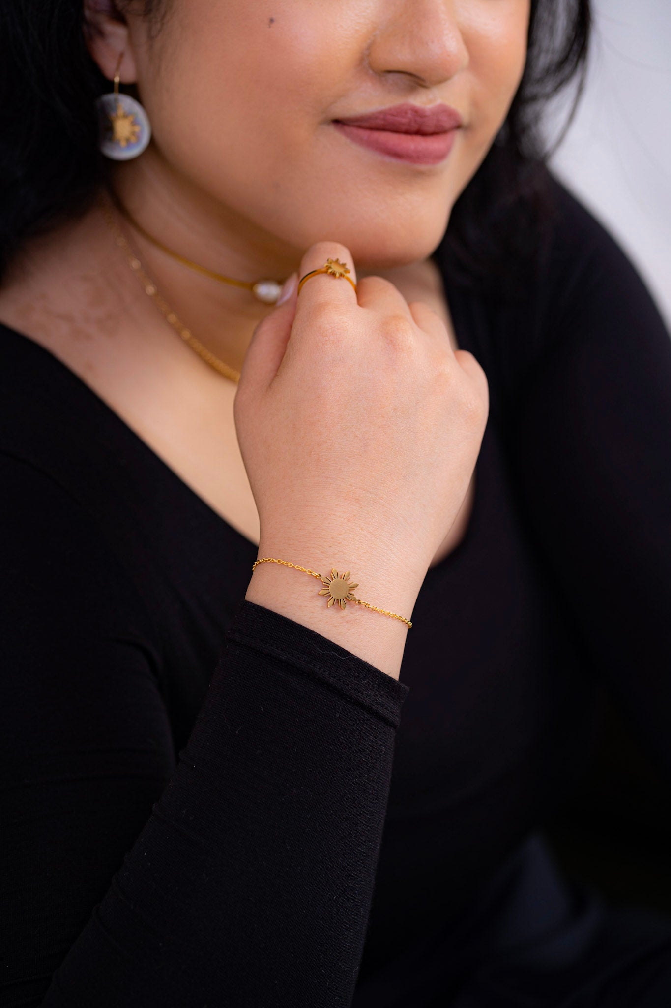 Close up of a woman’s wrist wearing the Araw gold and silver minimalist sun bracelets styled with a black outfit, highlighting the elegant metallic contrast.