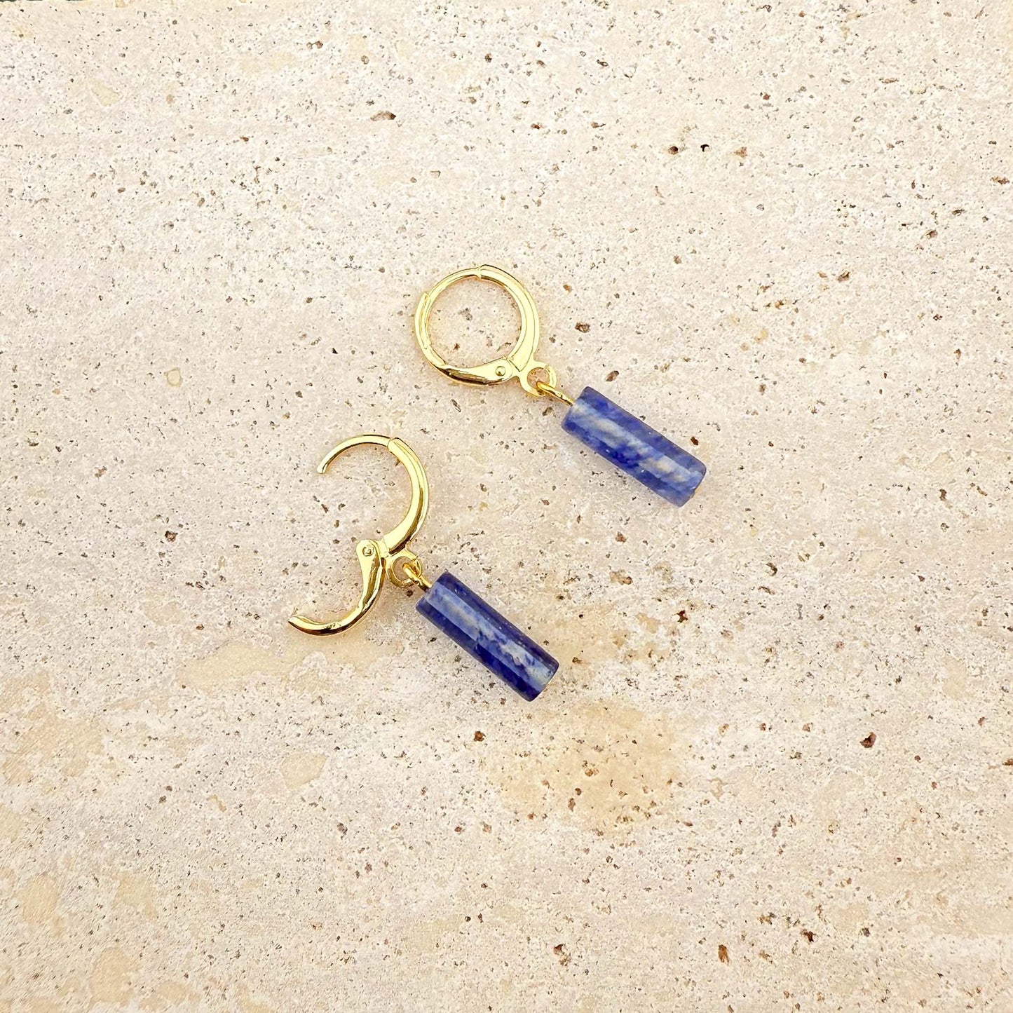 Gold blue watermelon column earrings on marble, with one huggie clasp open to show the secure hinge and post mechanism.