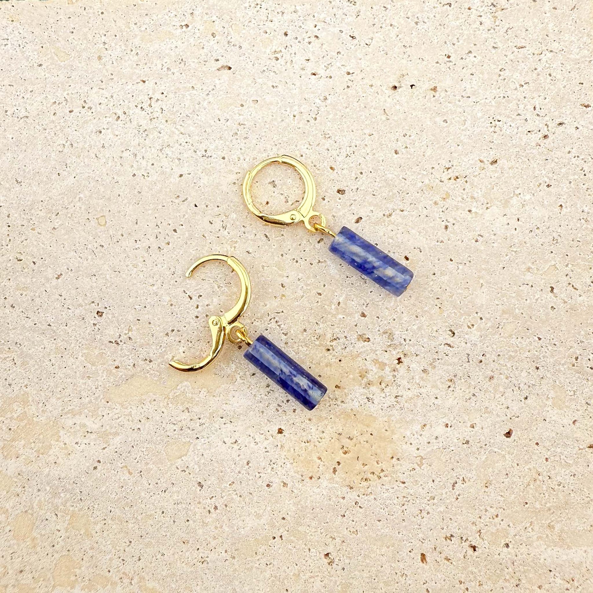 Gold blue watermelon column earrings on marble, with one huggie clasp open to show the secure hinge and post mechanism.